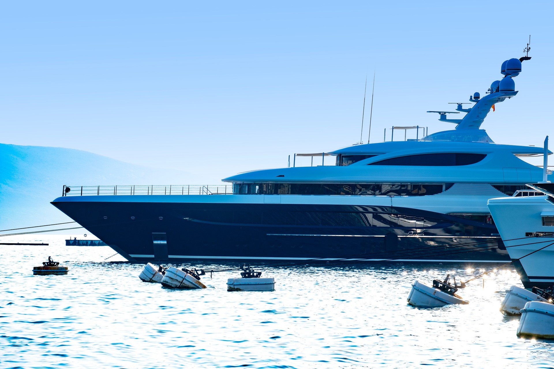 sleek luxury yachts lined up in coastal Modern Upscale marina, backed by port Montenegro, contemporary Tivat resort and towering green mountains